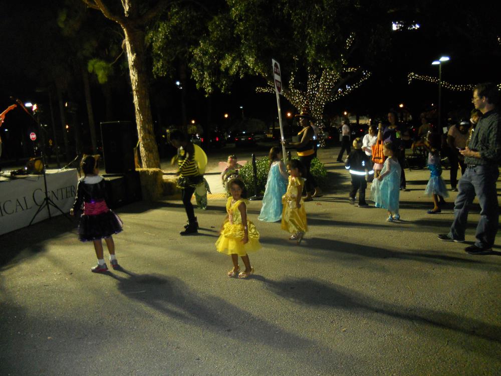 Children in Halloween costumes dance in front of band stage